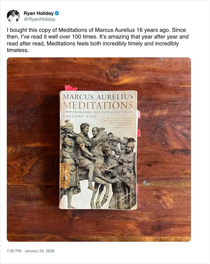 A well-worn copy of "Meditations" by Marcus Aurelius sits on a wooden table.